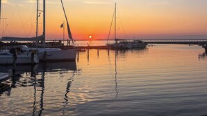 Un puerto deportivo con barcos amarrados, agua tranquila y un atardecer de fondo.