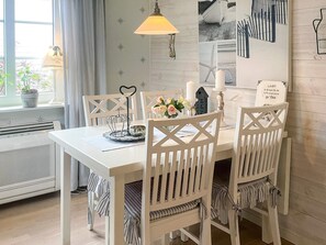 A dining area with a white table, chairs, a hanging lamp, and a wall with nautical-themed decorations. - 4 Star Holiday Home in Farjestaden (Farjestaden)