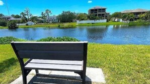 Un banco junto a un lago tranquilo con edificios al fondo.