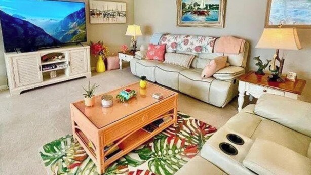 Una sala de estar con sofá, una mesa de centro, televisor y obras de arte en las paredes.