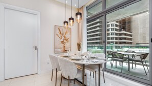 Un espace de salle à manger moderne avec une table ronde, des chaises et des luminaires suspendus.