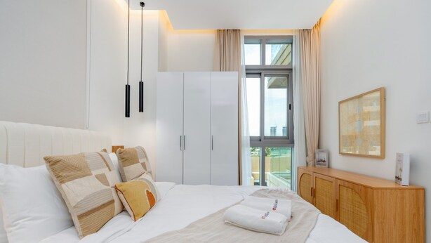 Une chambre d’hôtel comprenant un lit, une armoire, un meuble en bois, une fenêtre avec des rideaux et un tableau encadré au mur.