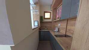 Eine kleine Küche mit Holzausstattung, einem Fenster und einer integrierten Spüle.