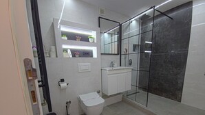 Ein modernes Badezimmer mit Toilette, Waschbecken und einer Duschkabine aus Glas.