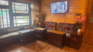 A room with a wooden desk, a television mounted on the wall, and a window with a view of buildings. - Juniper Mountain Resort (Lachen)