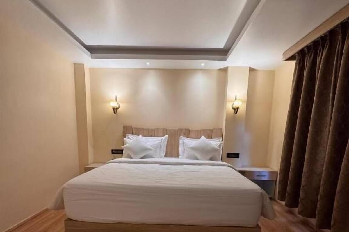 Ein Hotelzimmer mit einem großen Bett, Holzboden und zwei Wandleuchten.
