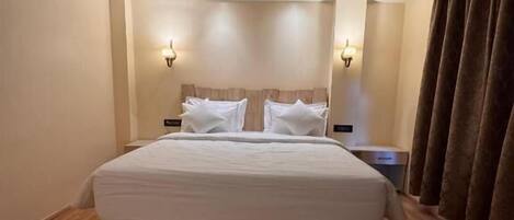 Ein Hotelzimmer mit einem großen Bett, Holzboden und zwei Wandleuchten.