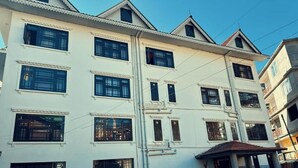 A multi-story building with a flat roof, multiple windows, and a covered entrance area. - Juniper Mountain Resort (Lachen)
