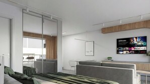 Quarto de hotel moderno com uma cama, sofás cinzas, arte na parede da TV e uma parede de destaque em madeira.