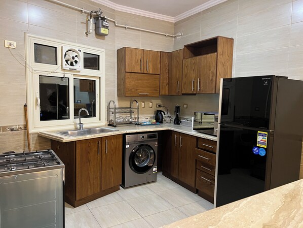 Una cocina con muebles de madera, lavadora, estufa y refrigerador.