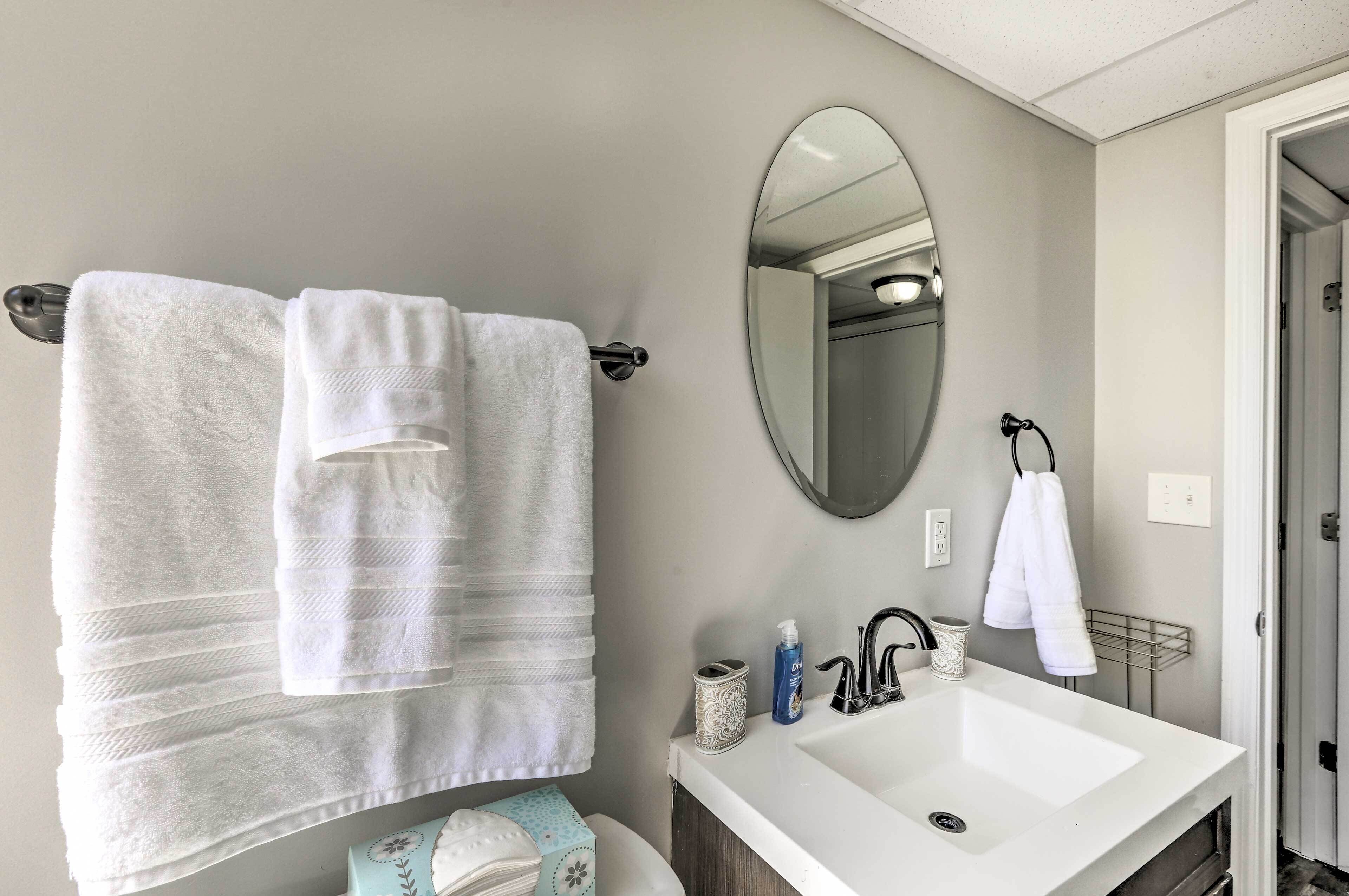Une salle de bain avec un lavabo blanc, un miroir et des serviettes suspendues à un porte-serviettes.