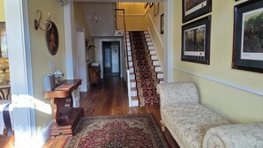 A spacious living room with a large rug, a staircase, and a chandelier. - Langdon Hill House (Gettysburg)