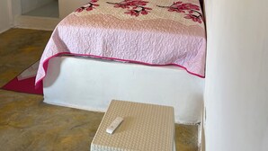 Une chambre à coucher avec un lit, un petit tabouret et un plafond en bois.