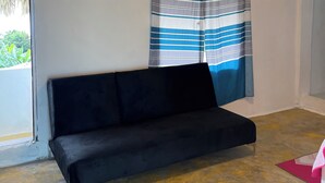 Une pièce avec un canapé noir, un rideau à motifs et un plafond en bois.