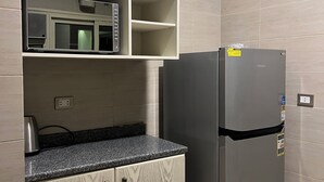 Eine Küche mit integriertem Mikrowellenherd, einem Edelstahlkühlschrank und einer Arbeitsplatte aus Granit.