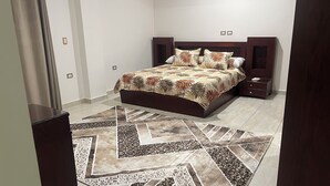 Ein Schlafzimmer mit einem Bett, Nachttischen, einem gemusterten Teppich und einem hölzernen Kopfseitenverkleidung.