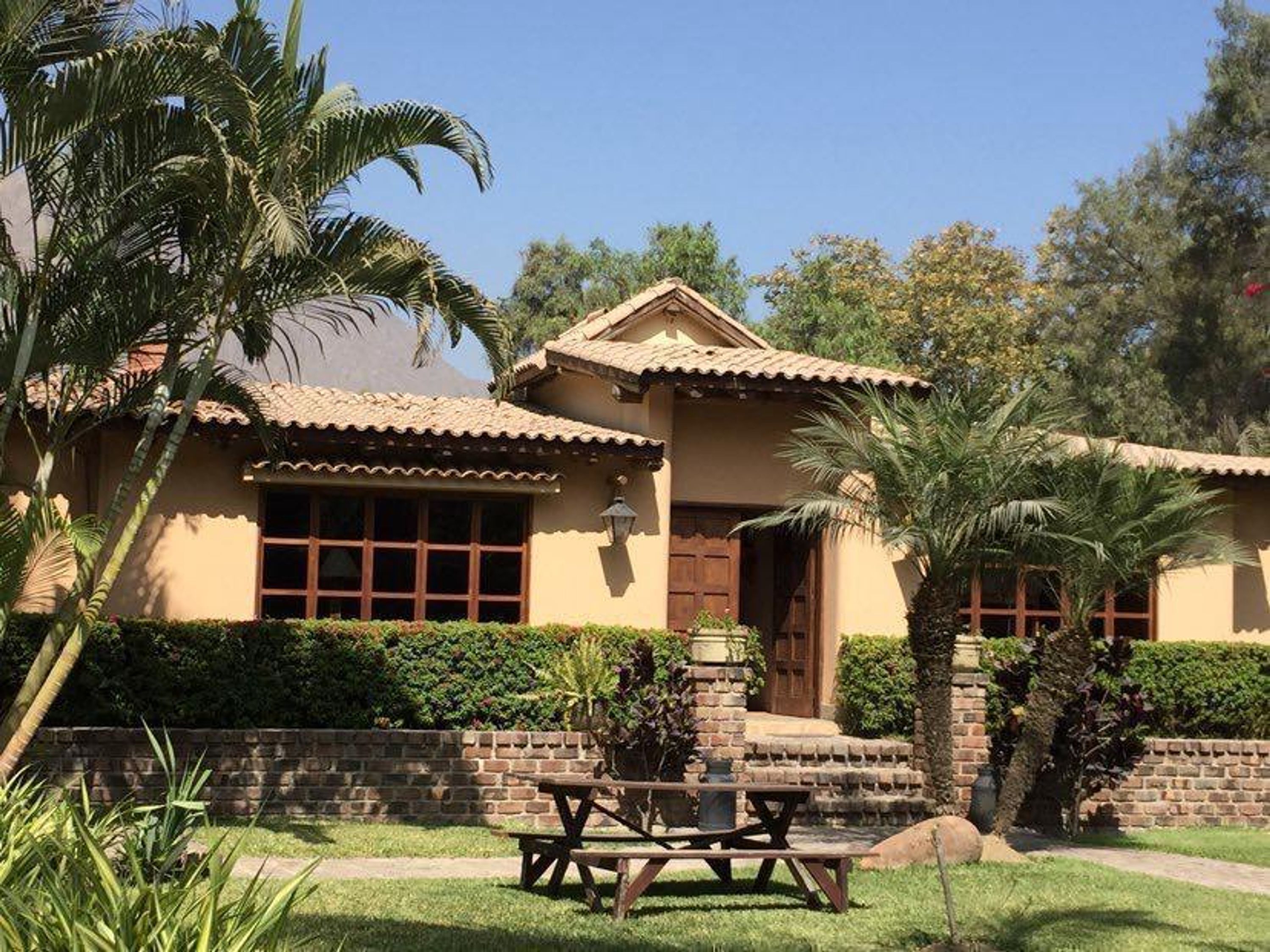 A two-story house with a tiled roof, a brick entrance, and a small patio with a table and chairs.