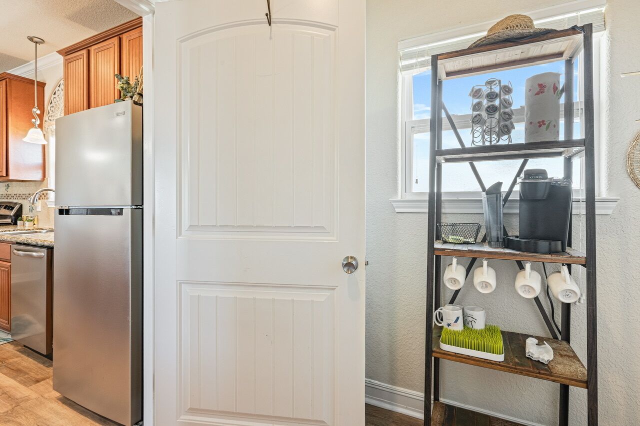 A kitchen with a stainless steel refrigerator, wooden cabinets, and a white door.