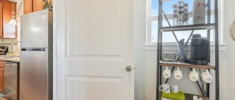 A kitchen with a stainless steel refrigerator, wooden cabinets, and a white door.