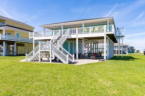 A two-story house with a covered porch, a staircase, and a small outdoor seating area. - Lil Bit Salty - 2nd Row - Amazing beach views and great outdoor space! (Crystal Beach)