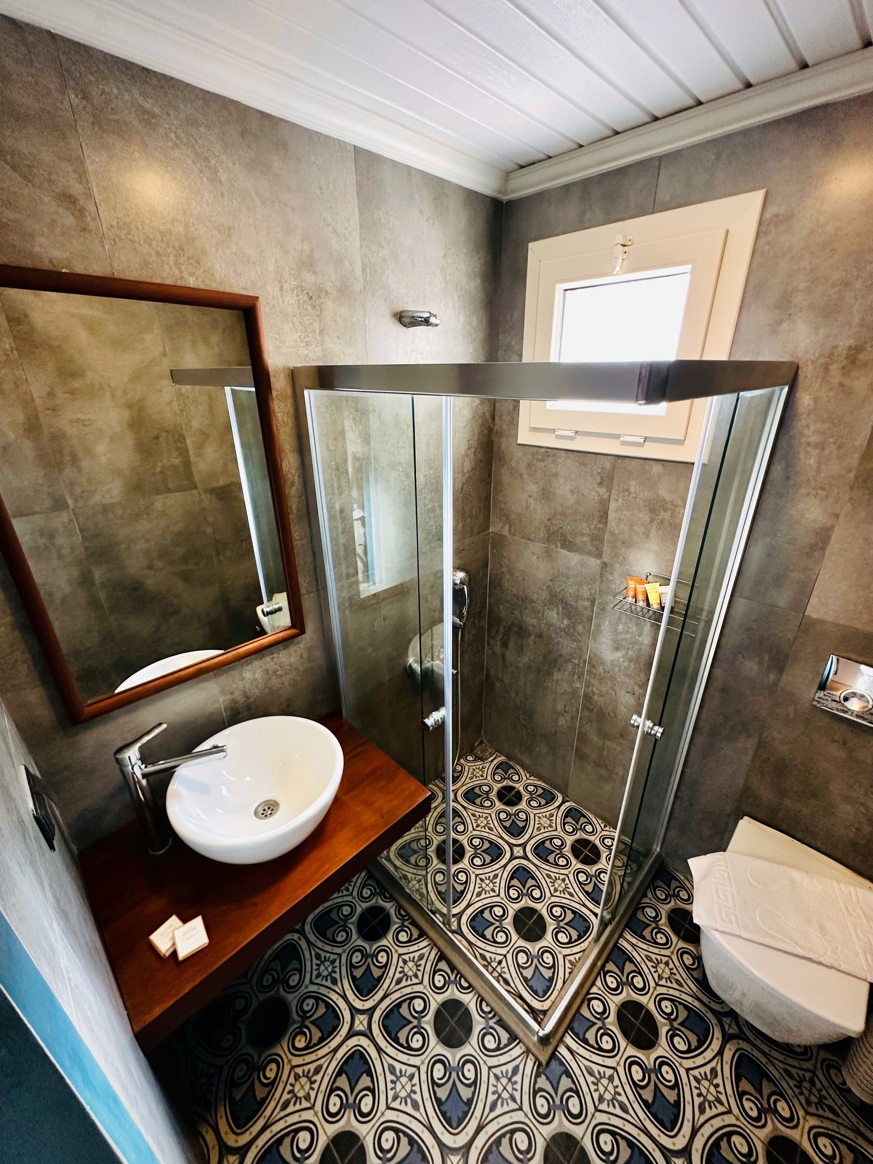 A bathroom with a glass shower enclosure, a sink, and a toilet.