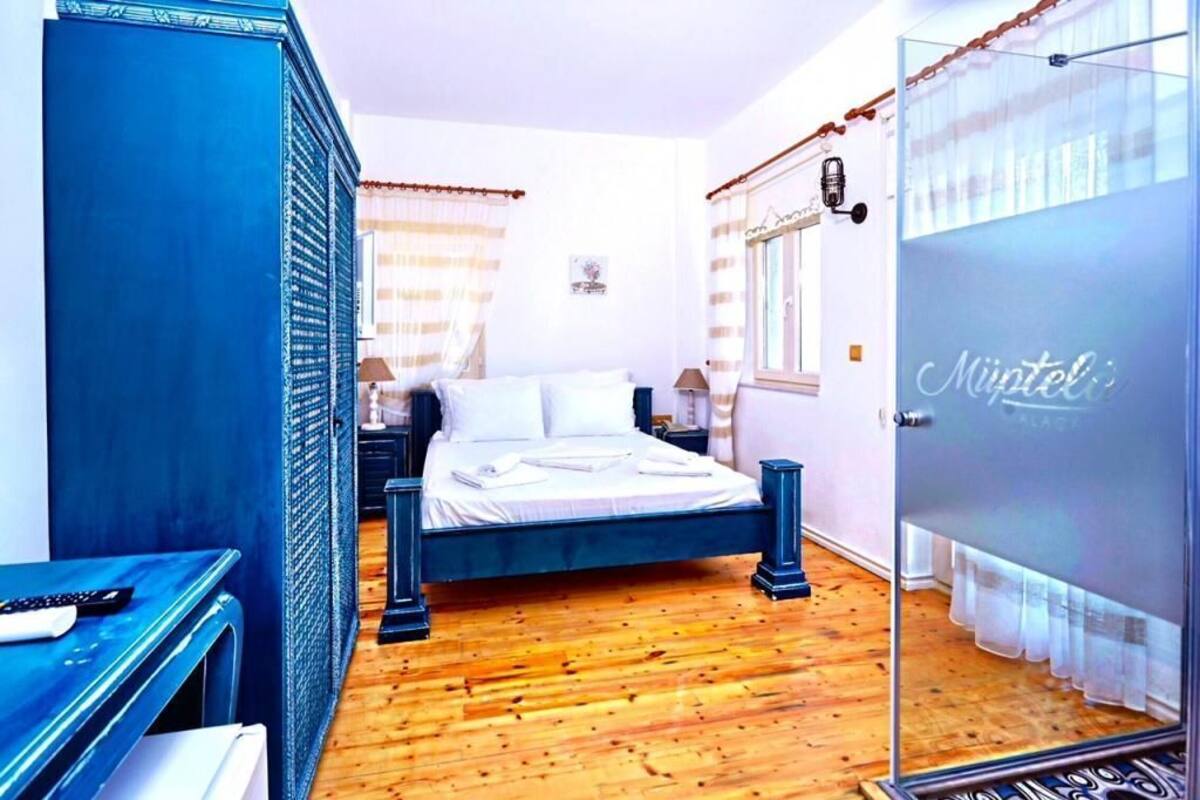 A bedroom with a bed, a desk, a wardrobe, and a glass door.