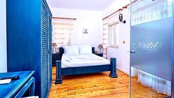 A bedroom with a bed, a desk, a wardrobe, and a glass door.