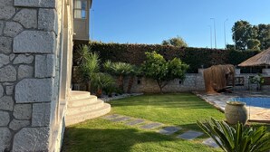 Un edificio in pietra con piscina, un prato curato e una scalinata in pietra che conduce all'ingresso.