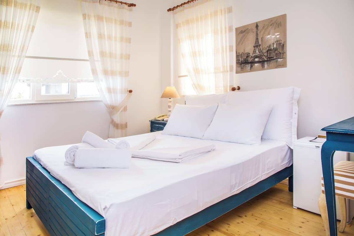 A neatly made bed with white linens, a bedside lamp, and a small table with a lamp.