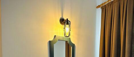 Une pièce comprenant une console en bois foncé, un banc, un miroir fixé au mur et un rideau.