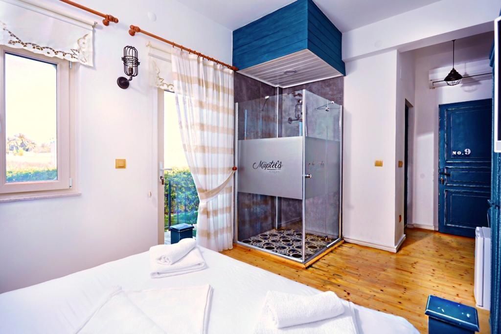 Ein Schlafzimmer mit Bett, Dusche und Blick ins Freie.