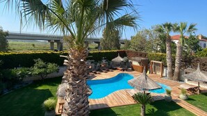 Un giardino con piscina, palme e un muro in pietra.