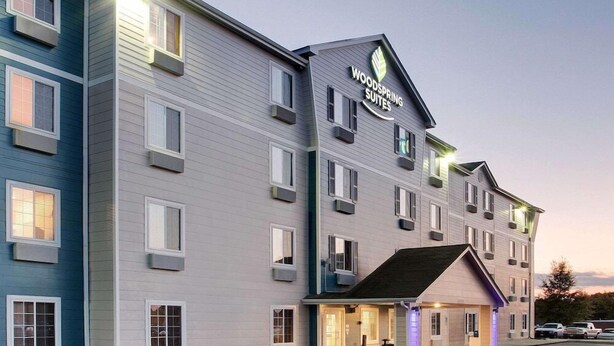 Un hôtel à plusieurs étages, sur lequel on peut lire l’inscription « Woodspring Suites ».