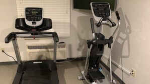 Une salle de sport à domicile équipée d’un tapis de course et d’un vélo elliptique.