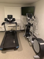 Un gimnasio en casa con una cinta de correr y una elíptica.