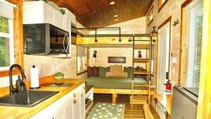 Cocina pequeña con microondas, lavamanos y encimera de madera.