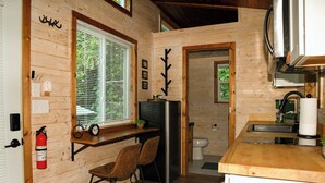 Cocina compacta con paredes de madera, un refrigerador, un lavamanos y una ventana con persianas.