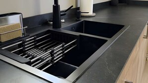 A modern kitchen with a black faucet, stainless steel sink, and a marble countertop.