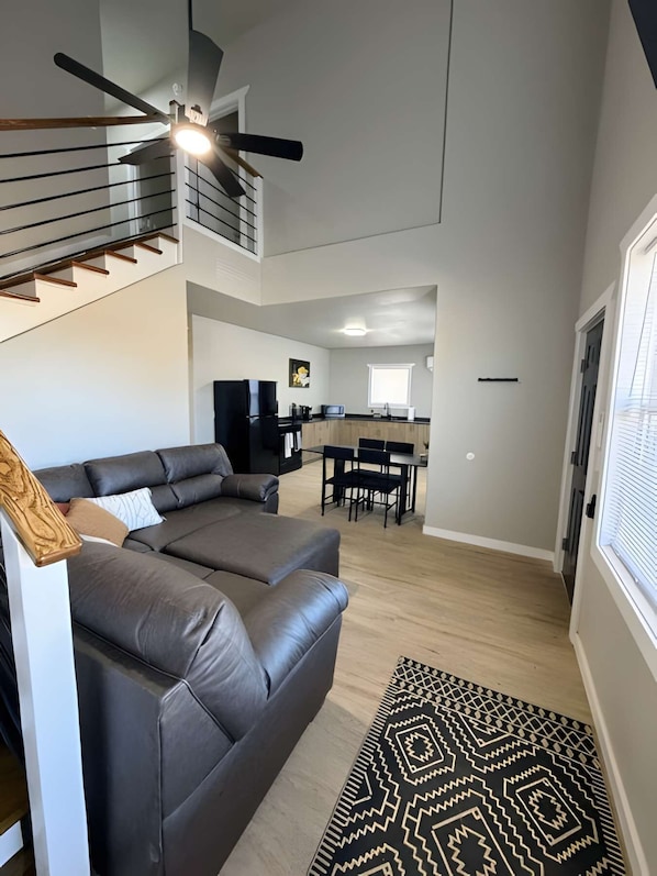 En moderne stue med en sofa, et spiseområde og et køkken i baggrunden.