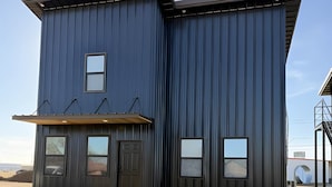 A modern two-story building with a flat roof, large windows, and a covered entryway.