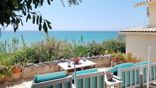 A terrace with a view of the sea, outdoor seating, and potted plants. - BLUE ESCAPE - Beachfront Privacy for Groups (12+ yrs) (Korission)