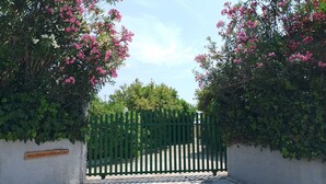 A gated entrance with a wooden signboard, a concrete pathway, and flowering bushes. - BLUE ESCAPE - Beachfront Privacy for Groups (12+ yrs) (Korission)