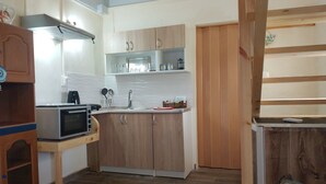 A compact kitchen with a microwave, sink, and wooden cabinets. - BLUE ESCAPE - Beachfront Privacy for Groups (12+ yrs) (Korission)