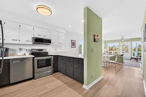 A modern kitchen with stainless steel appliances, a dining area with a table and chairs, and a view of the outdoors.