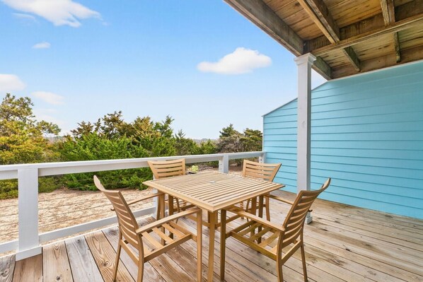 A wooden deck with a table and chairs, a white railing, and a blue building in the background. - Times Like These / 256a Brunswick Ave West 2 Bedroom Home (Supply)
