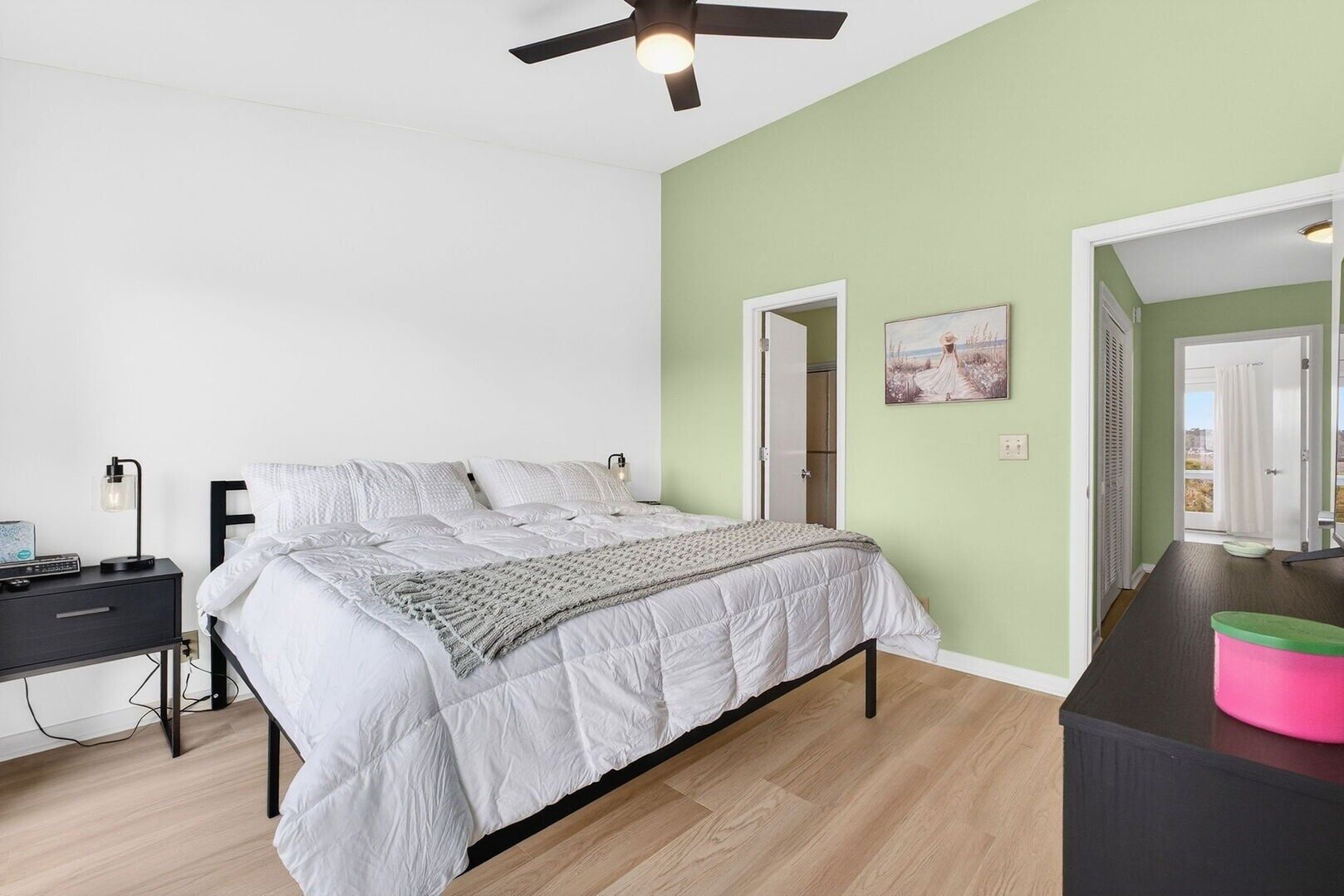 A bedroom with a bed, bedside table, lamp, and a ceiling fan.