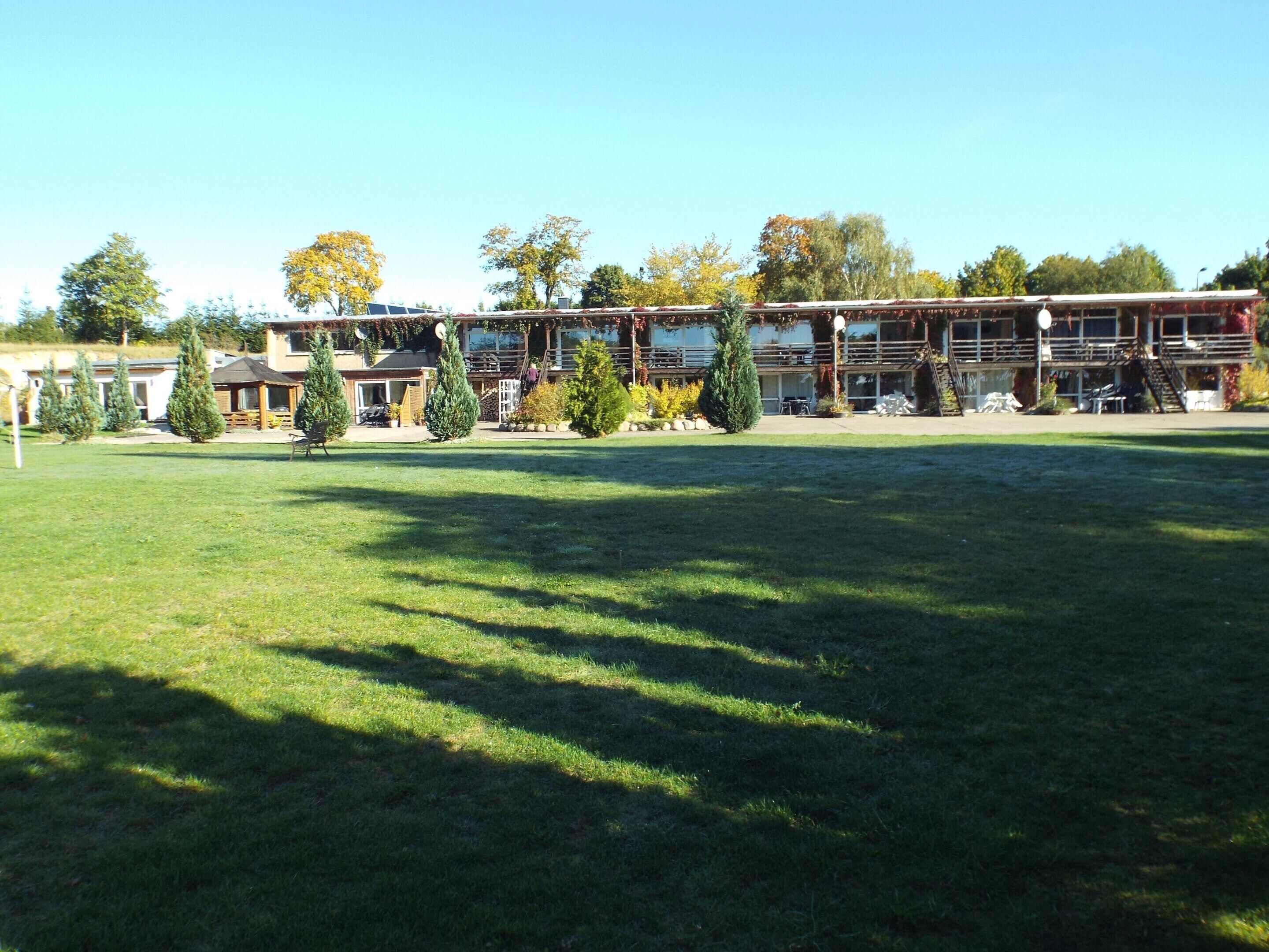 Un edificio de varios pisos, un espacio al aire libre cubierto y un campo de césped al frente.