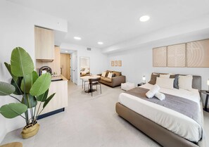 A modern hotel room with a bed, bedside table, and a large potted plant. - Brand New Condo | Rooftop Pool | 30th Floor Skyline Views (Miami)