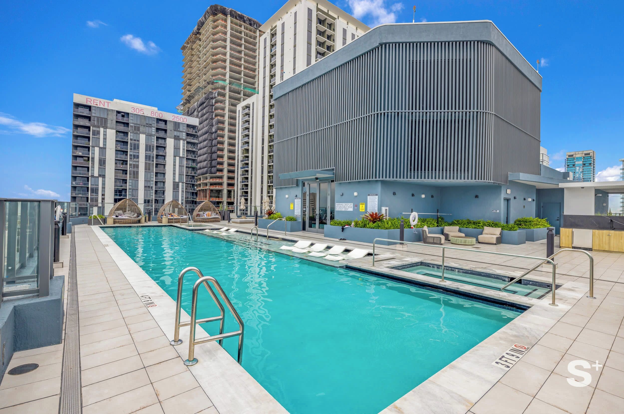 Expansive rooftop pool featuring poolside loungers and a modern architectural design set against surrounding high-rises.