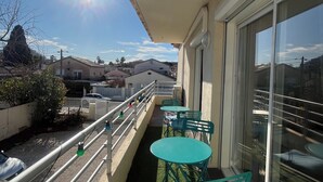 A balcony with green chairs and a table, a railing, and a view of the cityscape. - Bobo Chic Paradise (Villeneuve-Loubet)